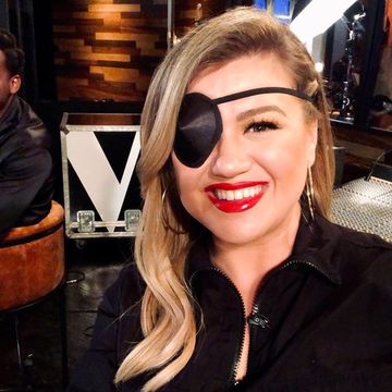 kelly clarkson sits with a black eye patch on her face in the background, 'the voice's leon bridges sits and smiles at the camera
