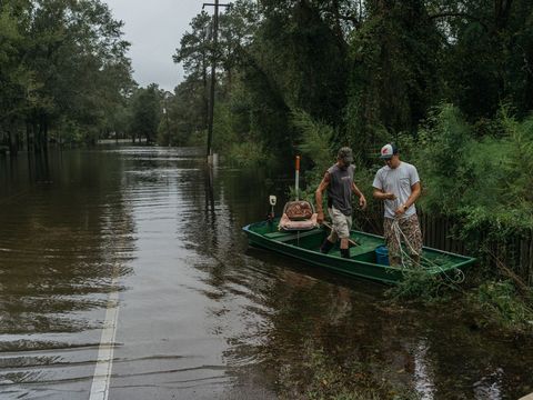 Aan het einde van hun straat in Vanceboro North Carolina maken Tyler Townsend rechts en zijn vader Mitch een boot vast Door de regen tijdens orkaan Florence trad de Swift Creek buiten zijn oevers en kwamen de straten onder water te staan