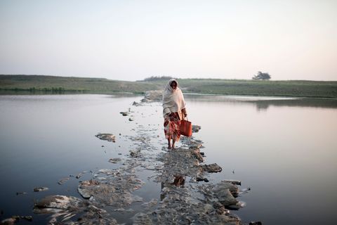 Via een brug van afval steekt een vrouw een geul van de Ganges over