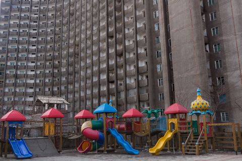 Kleurrijke speeltoestellen steken af tegen een grauw appartementengebouw in Pyongyang Guttenfelder zegt dat ondanks lange werkdagen en strak gecontroleerde privlevens mensen echt het beste proberen te maken van een verdomd moeilijke situatie
