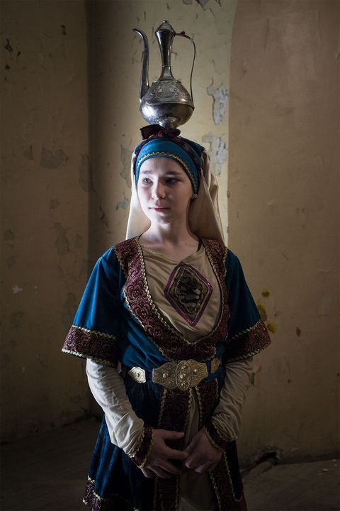 Gekleed in een traditioneel Dagestaans gewaad van brokaat traint de dertienjarige Patimat Murtazalieva haar evenwicht door een kan met water op haar hoofd te balanceren