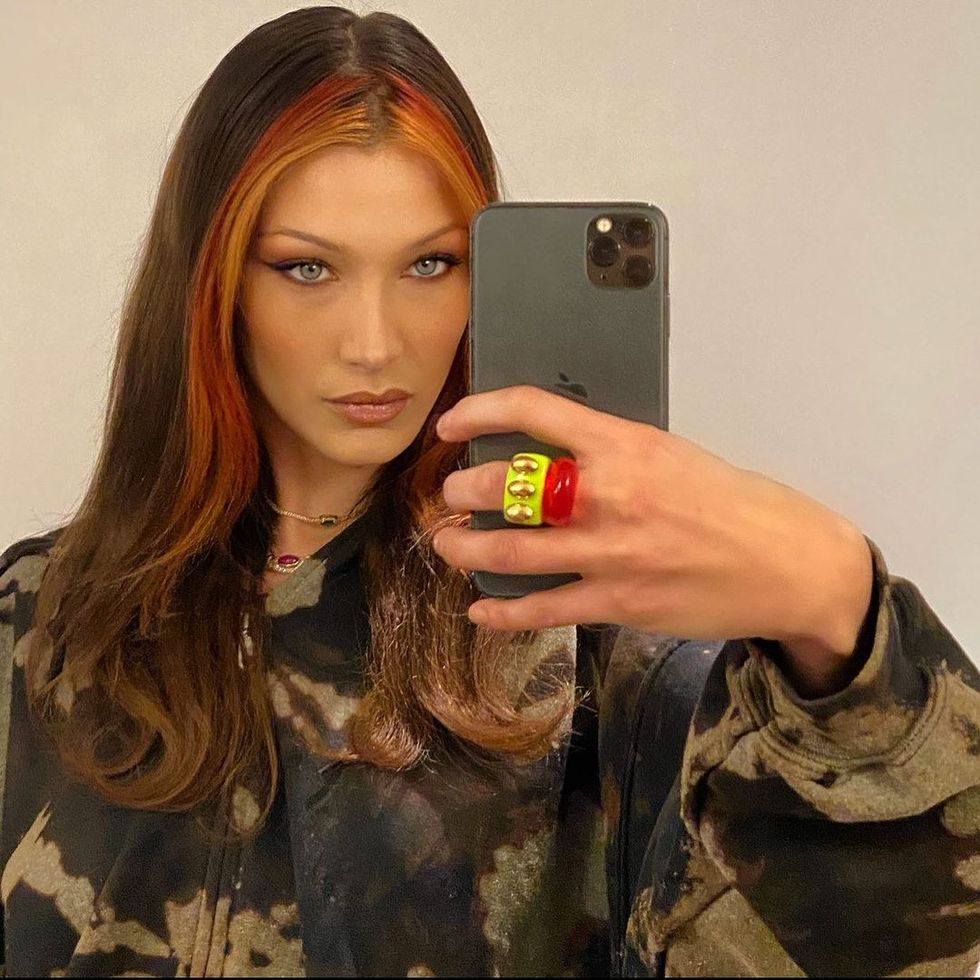 bella hadid taking a mirror selfie showcasing orange red money piece highlights