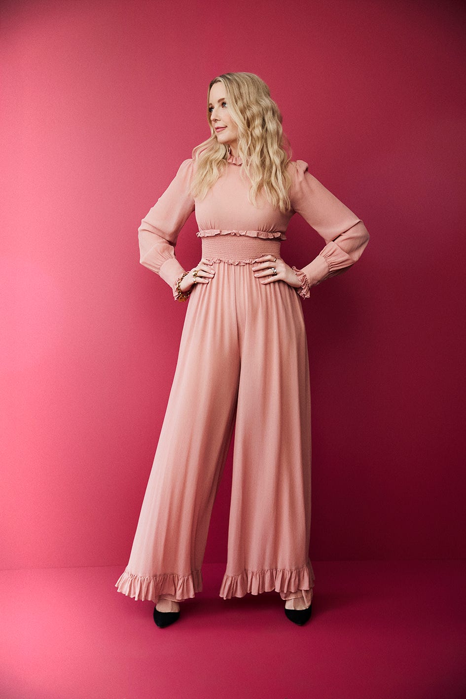 a woman stands confidently in a stylish pink outfit against a pink backdrop