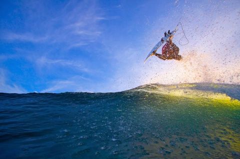 Voor de kust van Tahiti FransPolynesi maakt een surfer een hoge sprong met zijn surfplank