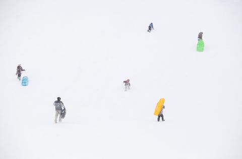 Sleerijders beklimmen een heuvel tijdens een sneeuwstorm in Flagstaff in Arizona