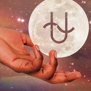 a hand holds out a moon with a u shaped glyph on it