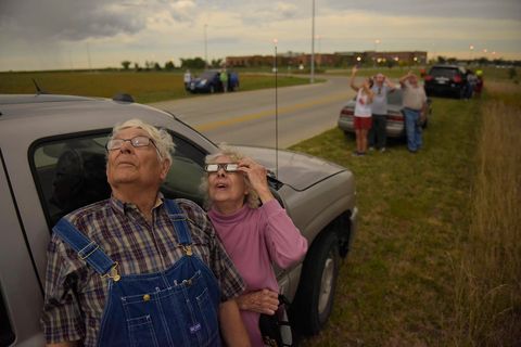 Samen met andere automobilisten die zijn gestopt langs een weg in de buurt van Beatrice Nebraska proberen Wilfred en Audrey DeVries de zonsverduistering door de bewolking heen te bekijken