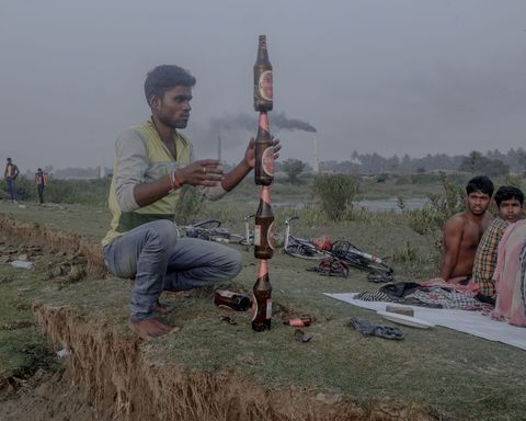 Een groep picknickt in een aangetast gebied bezaaid met steenovens rond de Ganges Grote overexploitatie van de rivieroevers heeft het erosieproces versneld