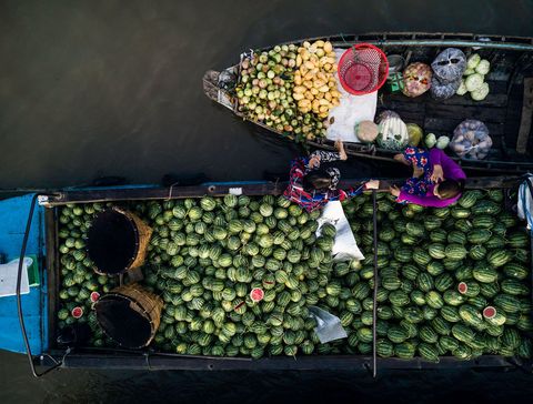 Wachtend op klanten maken twee verkopers een praatje op de drijvende markt van Phong Dien in de Mekongdelta
