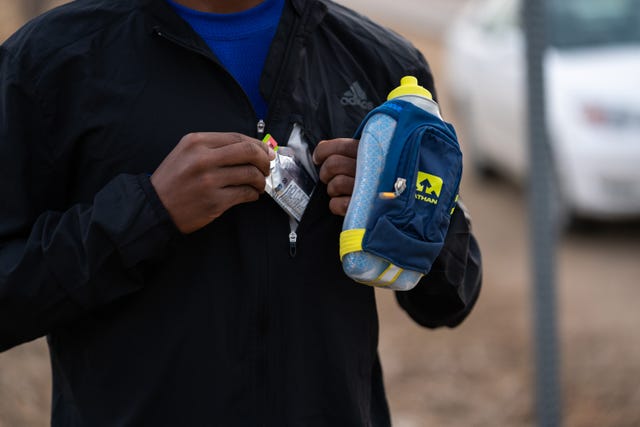 runner preparing to consume a sports gel while holding a hydration pack