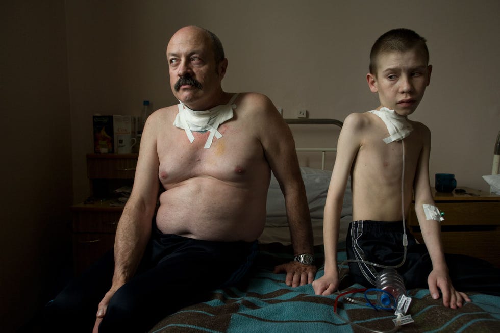 2005 Oleg Shapiro 54 en Dima Bogdanovich 13 lijden allebei aan schildklierkanker en worden verzorgd in een schildklierziekenhuis in Minsk waar dagelijks chirurgische ingrepen worden verricht Als liquidator werd Oleg blootgesteld aan extreme stralingsniveaus Hij onderging zijn derde schildklieroperatie Dimas moeder beweert dat de kernstraling van Tsjernobyl verantwoordelijk is voor de kanker van haar zoon maar zijn artsen zijn voorzichtiger ambtenaren in WitRusland krijgen vaak instructies om de ernst van de straling te relativeren