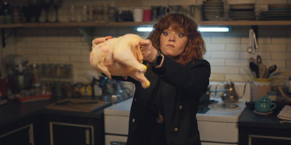 production still of actress holding up a chicken