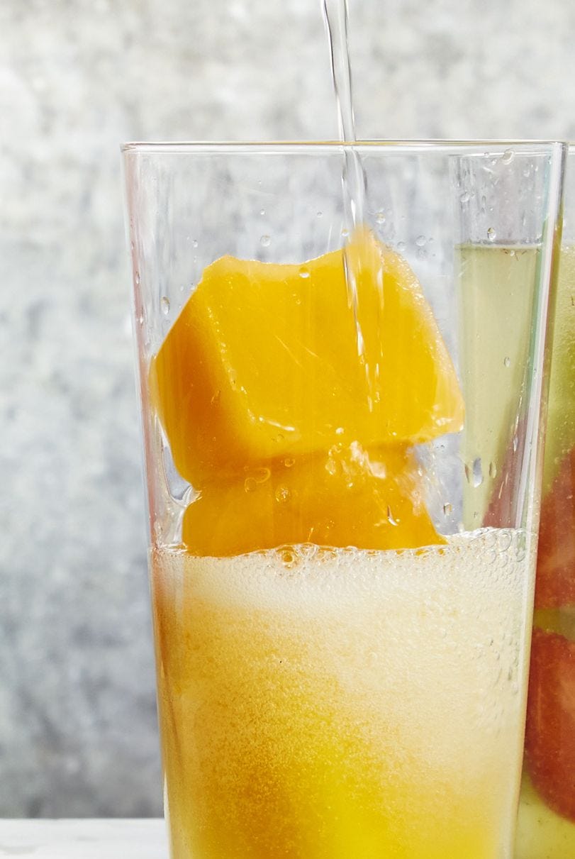 berry bellini ice cubes in a glass of champagne