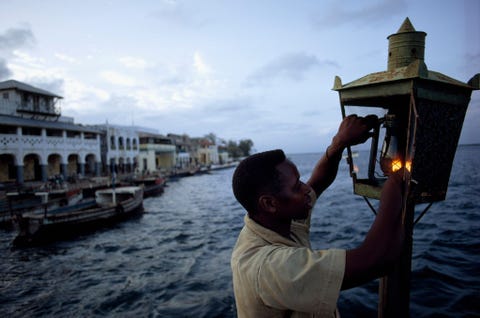 Een man steekt een lantaarn aan als baken om vissersboten de weg de wijzen naar de haven van het Keniaanse Lamu aan de Indische Oceaan