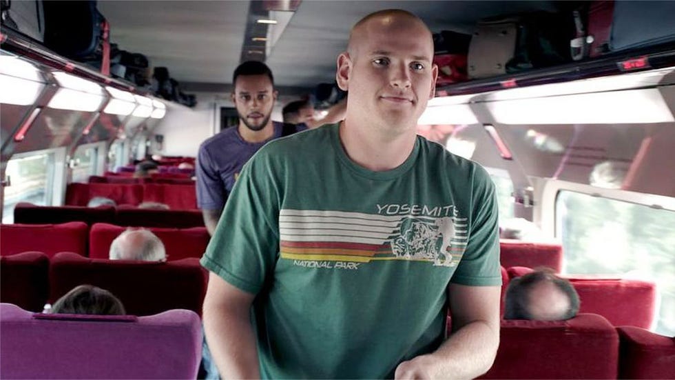 un hombre anda por el pasillo de un tren en la película the 1517 to paris