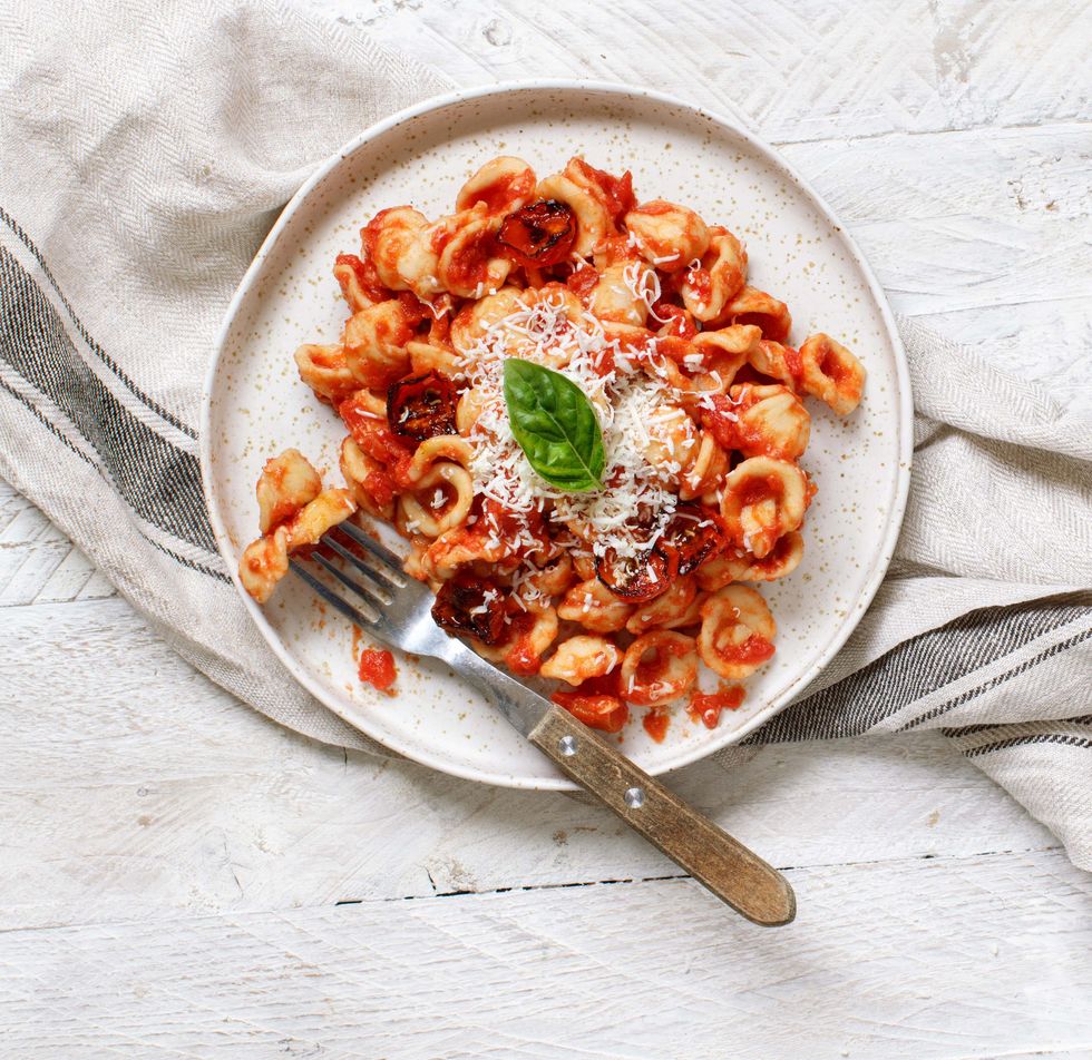 south italian pasta orecchiette with tomato sauce and cacioricotta cheese top view on a white wooden table