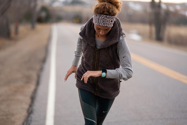 woman running and looking heart rate on watch
