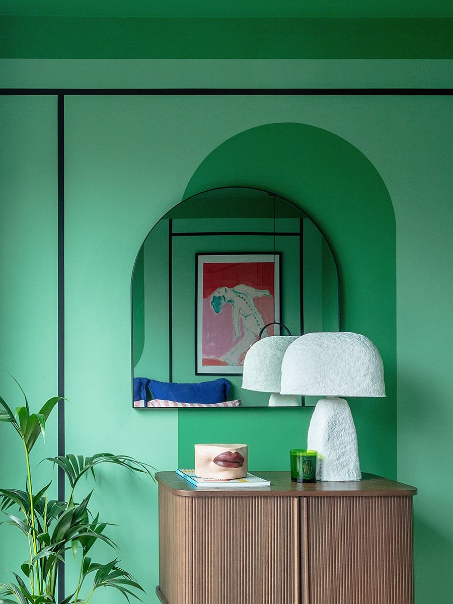 habitacion verde con comoda de madera y lampara de ceramica blanca