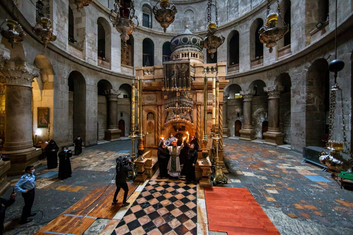 De eerwaarde vader Arbak Saruchanjan van de ArmeensApostolische Kerk houdt het Heilig Vuur omhoog terwijl hij opduikt uit de Aedicula het tempeltje binnenin de Heilig Grafkerk waaronder zich volgens de overlevering het graf van Jezus Christus bevindt