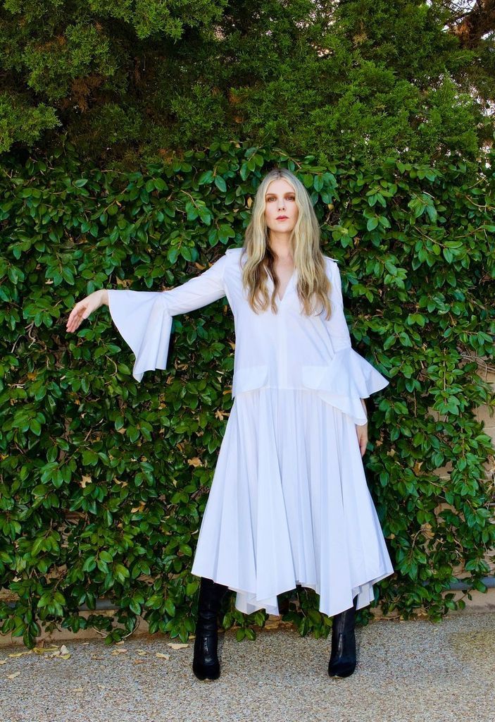 lily rabe in white dress and black boots facing forward