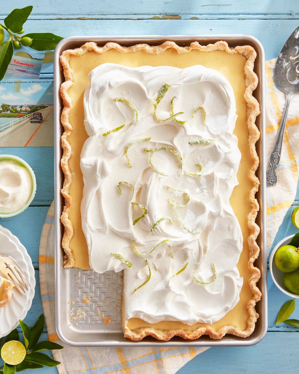 key lime slab pie topped with whipped cream and candied lime zest with a corner piece removed