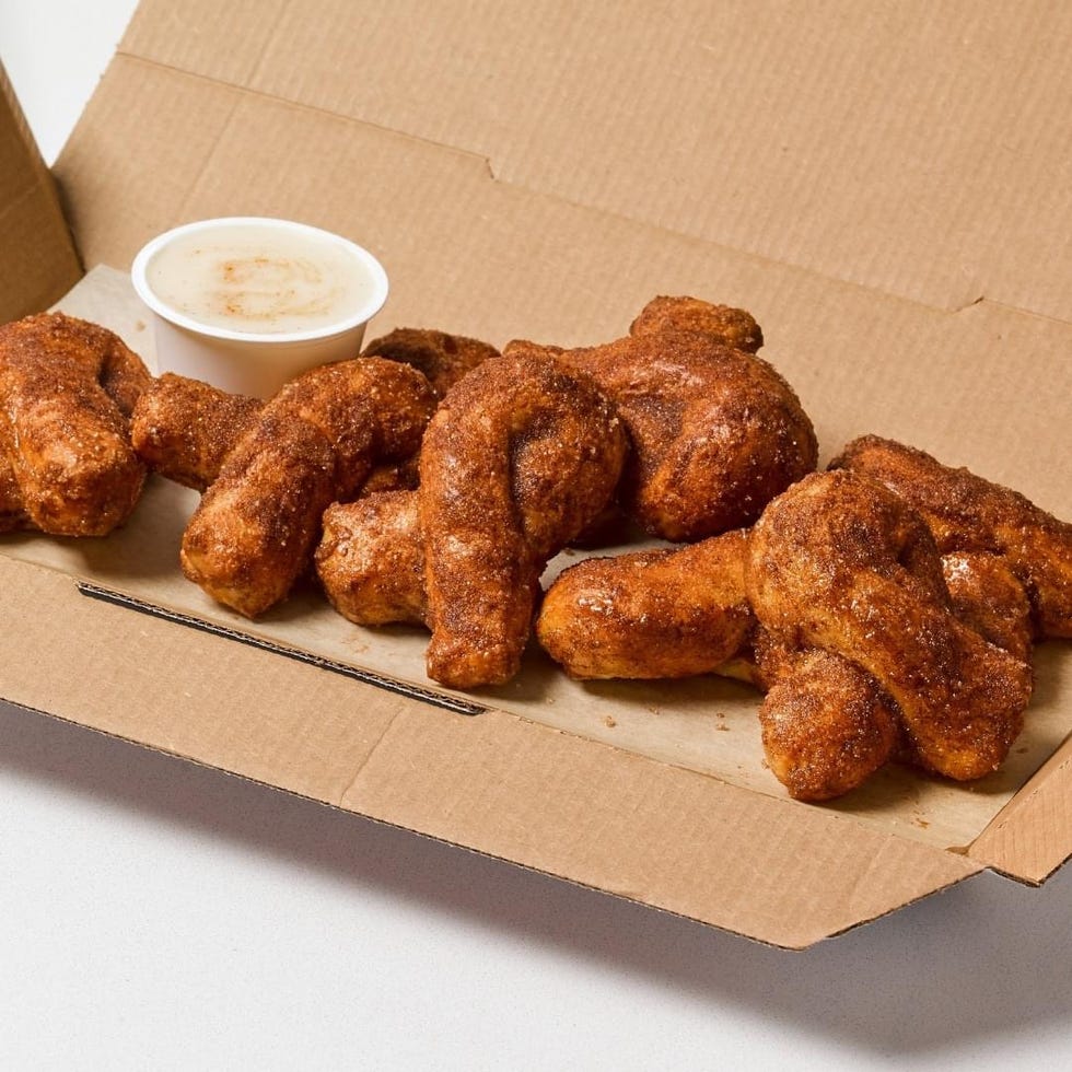 a box containing several cinnamon sugar coated doughnut twists and a small container of dipping sauce
