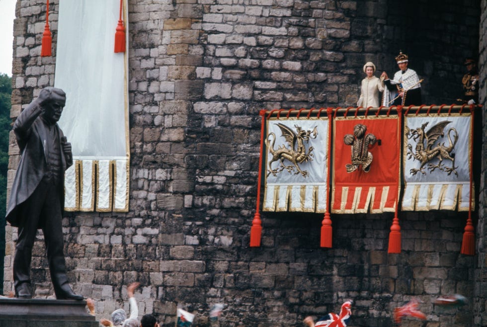16604 Na de plechtige ceremonie waarbij kroonprins Charles als Prince of Wales is genstalleerd in 1969 wuiven Elizabeth II en prins Charles naar de menigte Hoewel Charles de titel ontving vond de ceremonie plaats tegen de achtergrond van een groeiend Welsh nationalisme