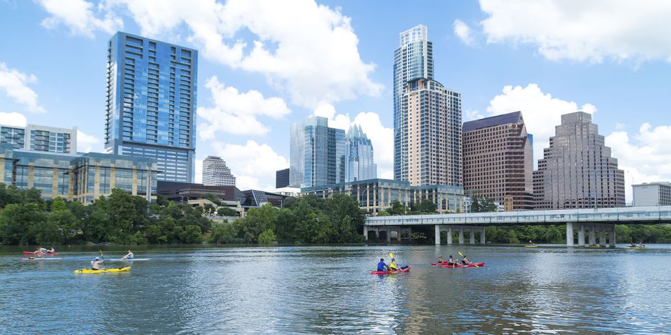 a distant view of people canoeing on lady bird lake in austin texas with the austin skyline in the background