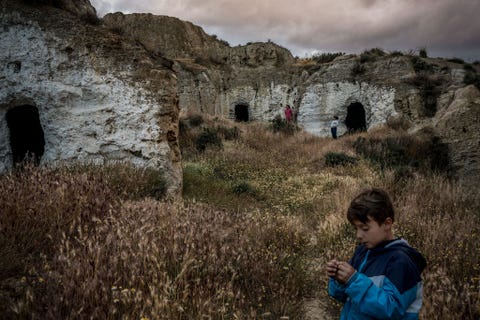 Kinderen spelen naast hun eigen grotwoning in enkele verlaten grotten In het verleden waren alle grotten bewoond maar nu staan veel van deze woningen in het dorp leeg