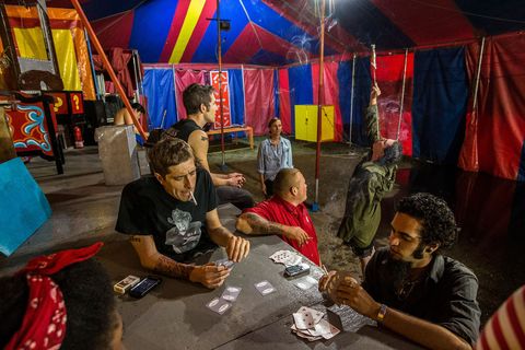 Artiesten van de rondreizende show spelen een kaartspel in een tent terwijl ze wachten totdat een storm is overgewaaid