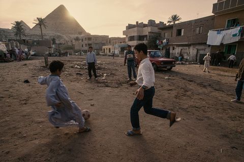 Dorpskinderen spelen voetbal aan de voet van de piramiden van Gizeh in Egypte