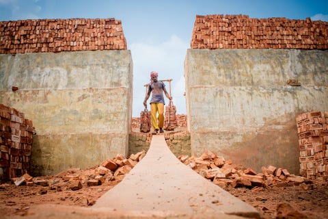 Een arbeider in Bangladesh draagt een stapel bakstenen uit de oven naar buiten Het land groeit gestaag en heeft voortdurend bouwmaterialen nodig