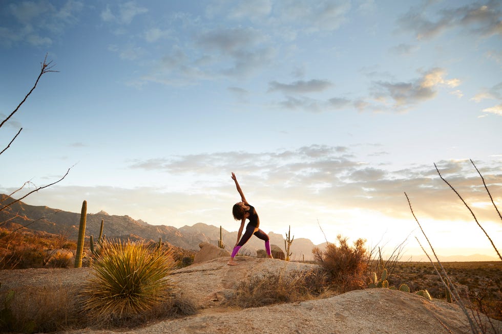 individual practicing yoga in a desert landscape at sunset