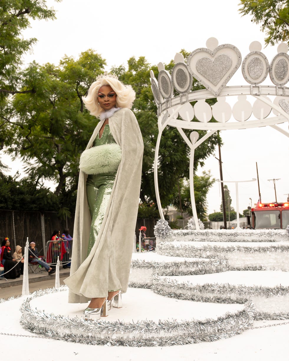 a woman standing on a parade float smiling at the camera