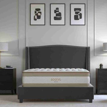 a bed with a white sheet and pictures on the wall