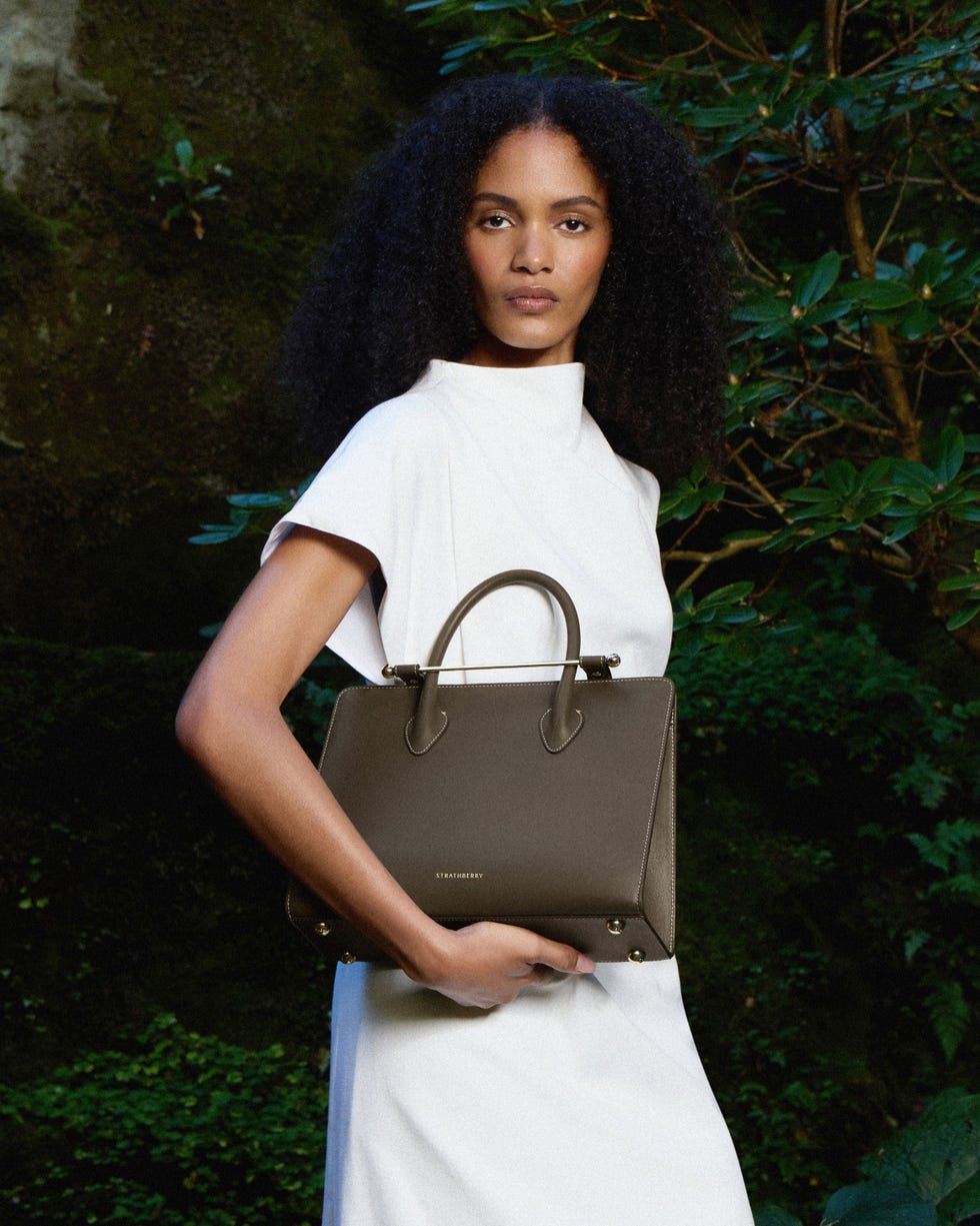 a person poses with a handbag in a natural setting