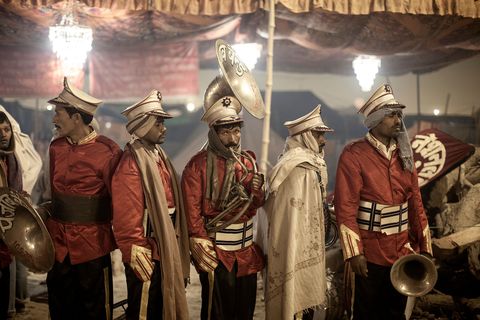 Een groep muzikanten bereidt zich voor op een optreden voor een menigte mensen die tijdens de Kumbh Mela op een sadhoe of heilig persoon wacht