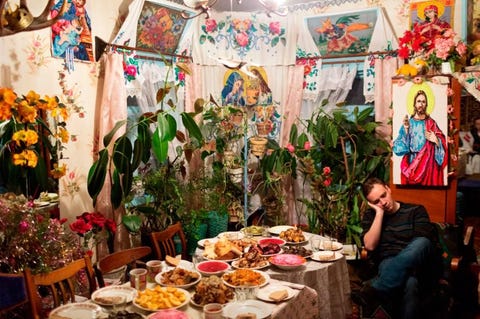 Een man dommelt weg bij een tafel vol etenswaar tijdens de viering van kolyada een seculier feest dat is opgenomen in het Oostersorthodoxe kerstfeest