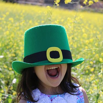 little girl with brown hear wearing a green leprechaun hat for st patricks day