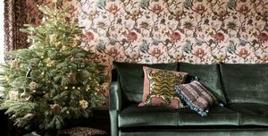 Living room with green velvet sofa and Christmas tree against floral patterned wallpaper
