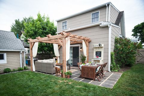 large pergola in a backyard with sofa and dining set