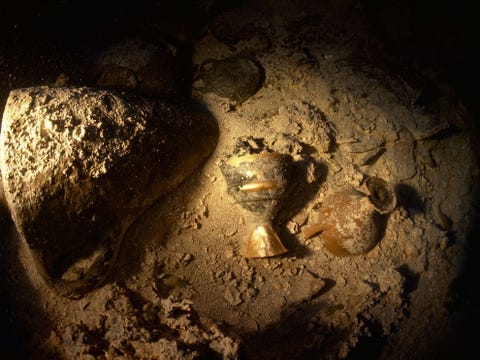 Aan weerszijden van een gouden kelk liggen een amfora links en een drinkschaal met twee handvaten van het type kylix rechts tussen andere wrakstukken van een koopvaardijschip uit de oudheid Het circa vijftien meter lange schip was beladen met kostbaarheden en goederen toen het rond 3400 jaar geleden in de Middellandse Zee voor de kust van Turkije zonk