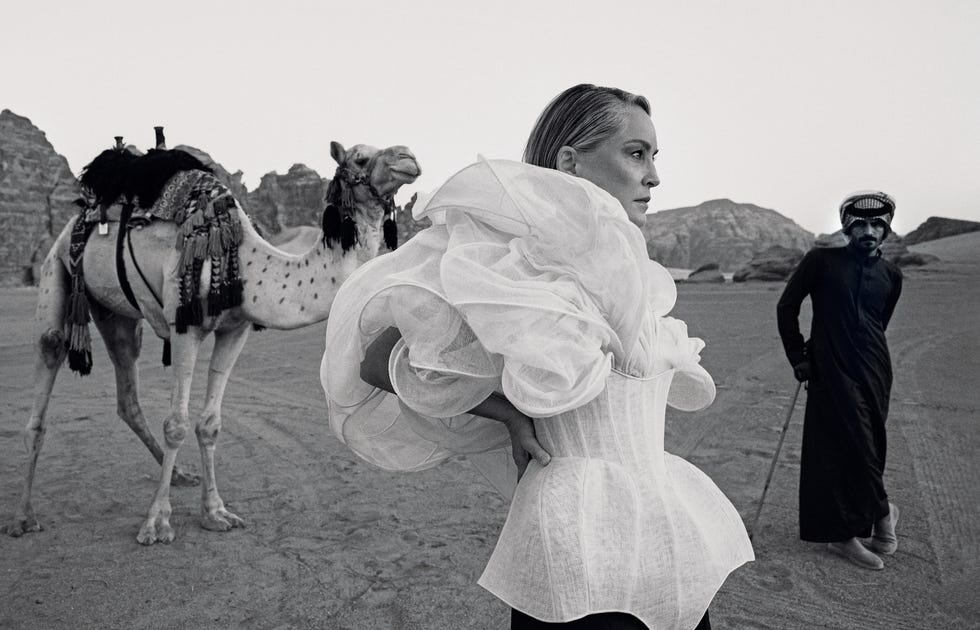 a woman in a wedding dress walking with a man in a tuxedo and a horse