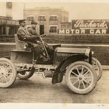 1904 packard model l with driver and passenger in front of packard plant in detroit