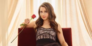 bachelorette katie thurston sits on a chair with a rose