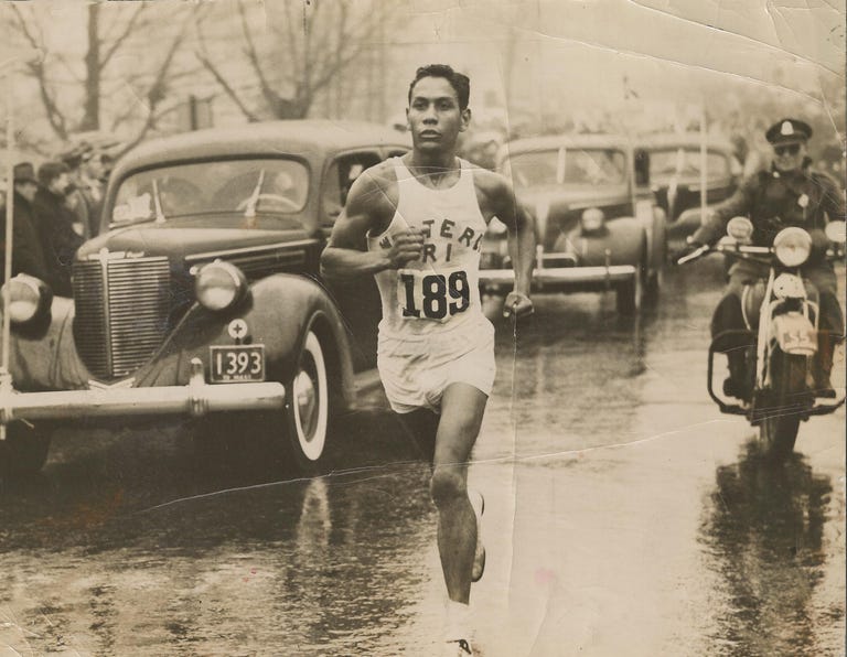 runner competing in a race on a rainy day with classic cars in the background