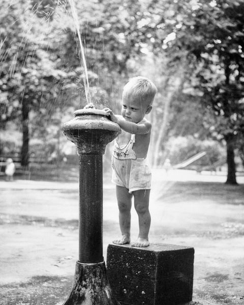 1950s little boy playing in water fountain