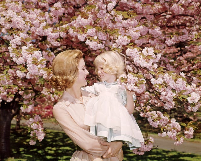 1950s 1960s redhead mother holding blonde girl daughter among cherry tree blossoms (photo by h. armstrong roberts/classicstock/getty images)