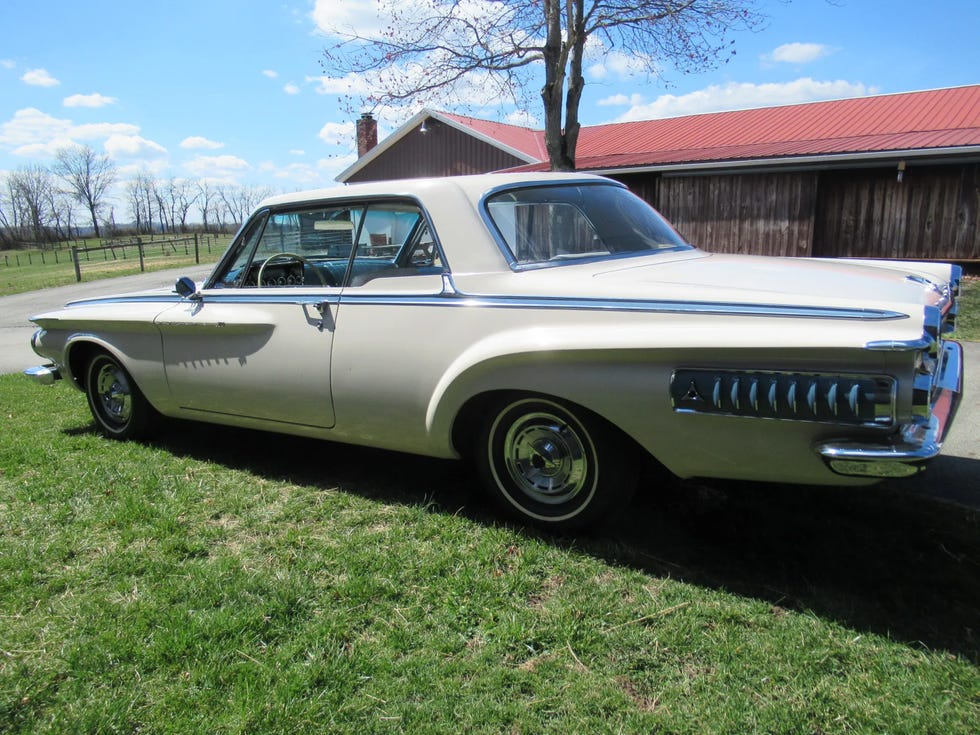 rear three quarter view of a white 1962 dodge polara 500, showcasing tail fins and chrome details, parked on grass.
