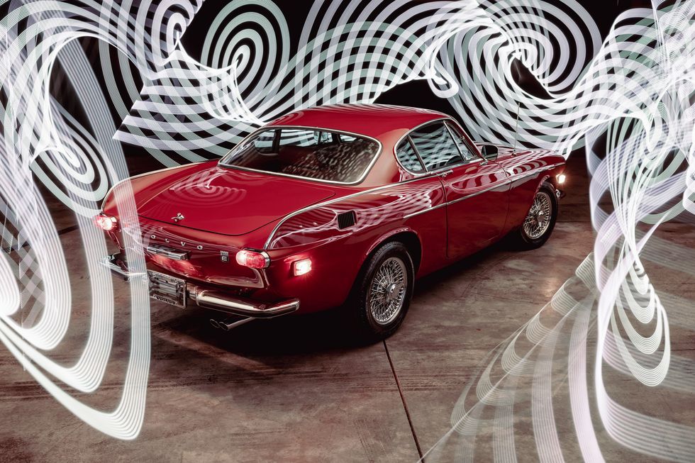 a light painting photograph of a ruby red 1970 volvo 1800e taken by bring a trailer photographer teddy pieper
